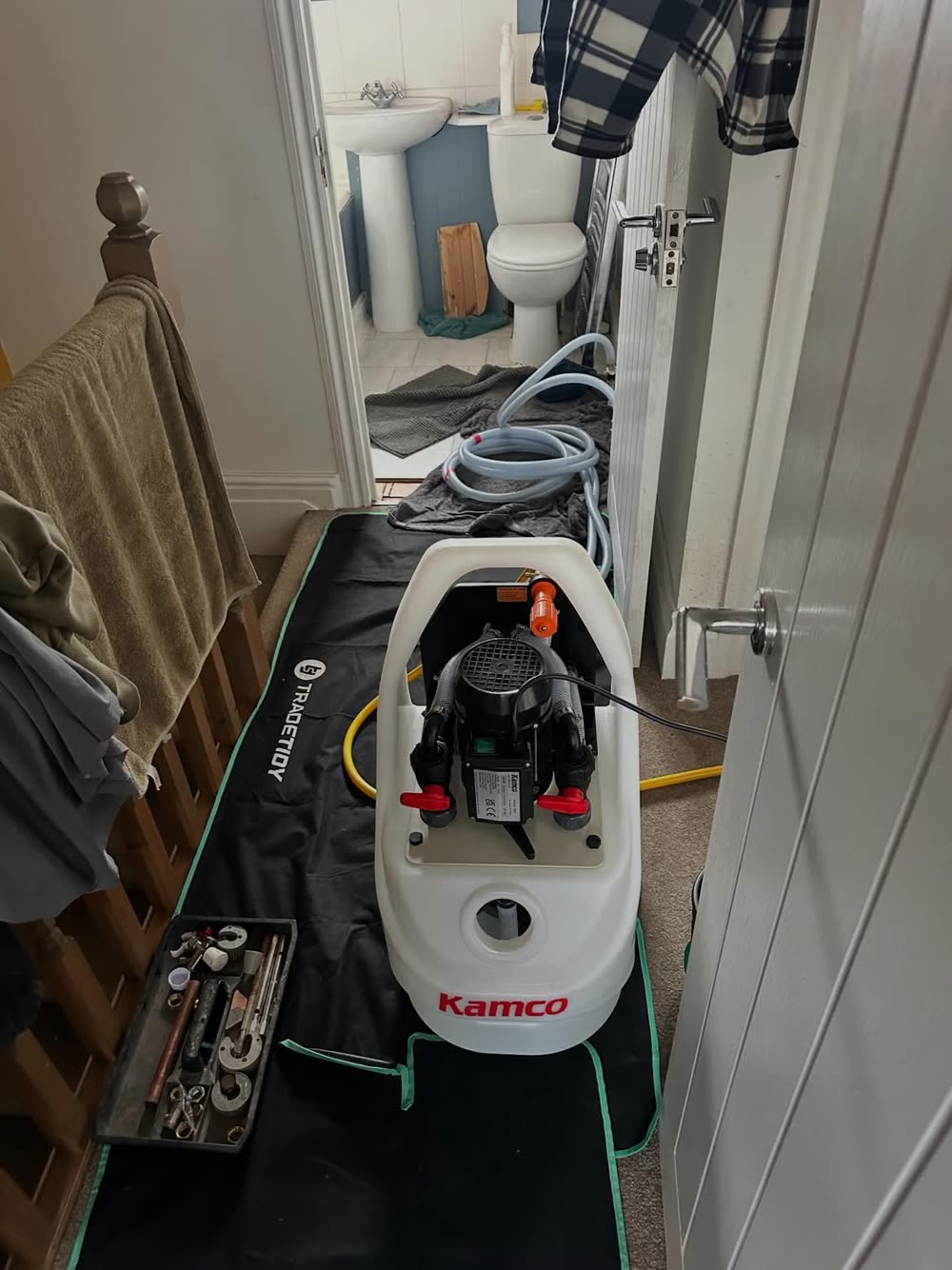 Bomba Kamco instalada dentro de una vivienda sobre cubrepiso protector, con mangueras conectadas al circuito